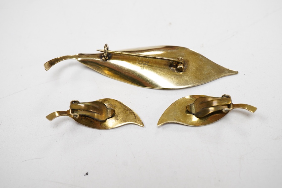 A Norwegian gilt white metal and red enamel demi parure, by David Andersen, comprising a leaf shaped brooch, 65mm and a pair of matching ear clips.